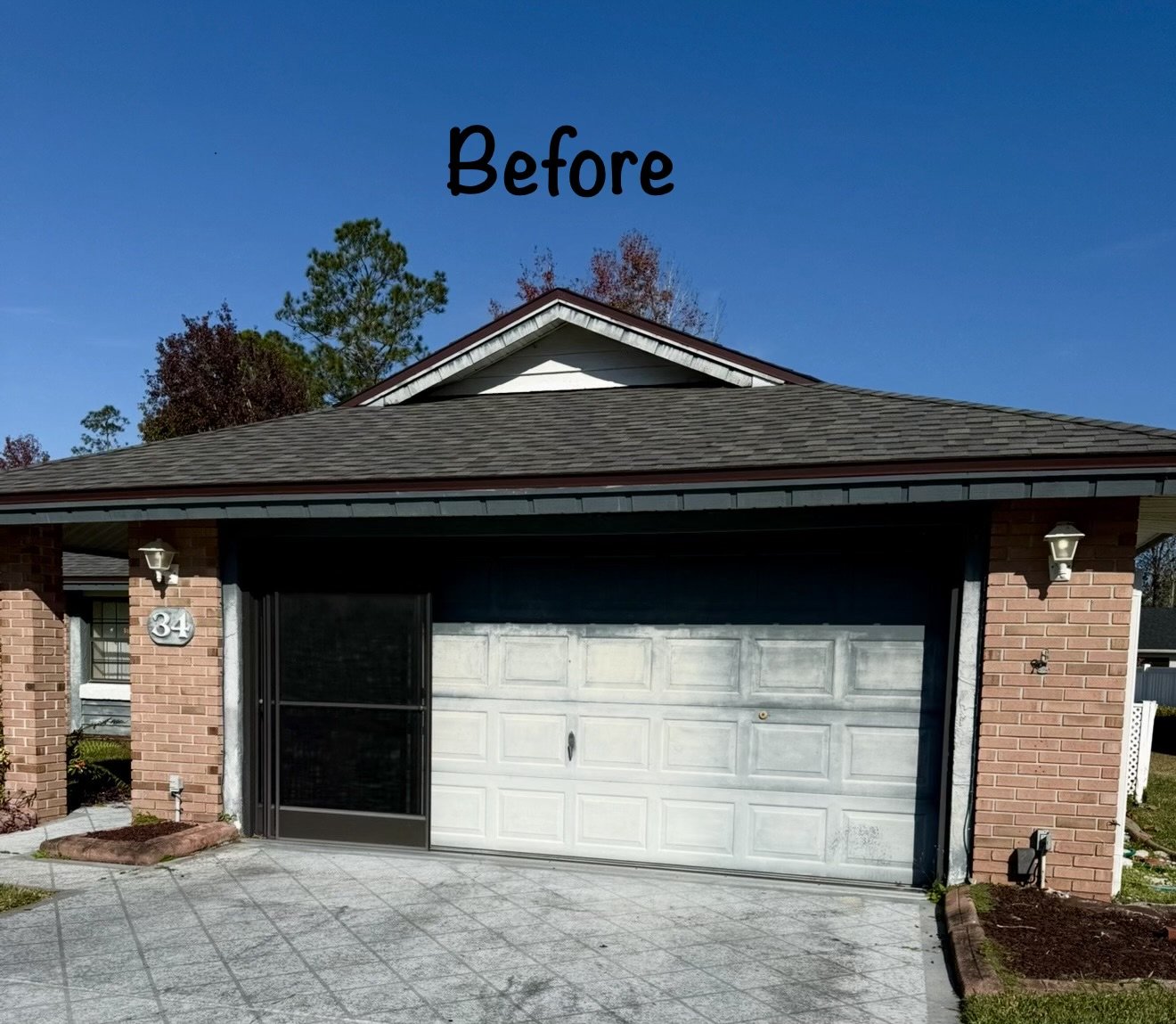 Garage exterior before repainting, faded white door and brick trim